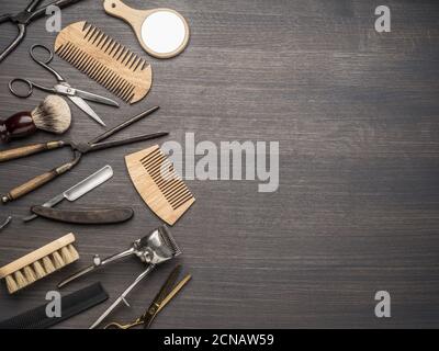 Klassische Grooming- und Frisierwerkzeuge auf Holzhintergrund. Draufsicht auf Barbershop-Instrumente, die auf dunklem Holztisch liegen. Stockfoto