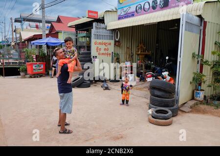 Kambodscha, Siem Reap 12/08/2018 ein Mann mit einem Kind in den Armen in der Nähe der Reifengeschäft, Slums von Asien, Bewohner von armen Gebieten der Stadt Stockfoto