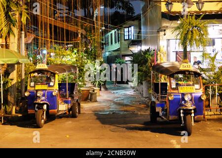 Bangkok, Thailand, 28. Dezember 2018. Tuk-Tuk, eine automatische Rikscha. Kleine asiatische Taxis stehen nachts auf einer Stadtstraße. Stockfoto