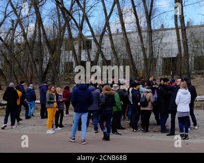 Tschernobyl, Ukraine, 14. März 2020. Eine große Gruppe von Touristen vor einem alten verlassenen Gebäude. Menschen unterschiedlichen Alters und Geschlechts. Reisende in Stockfoto