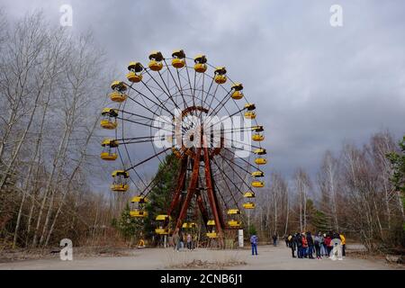 Pripjat, Ukraine, 14. März 2020. Touristen in der Nähe der berühmten Riesenrad in einem verlassenen Vergnügungspark in Pripyat. Wolkiges Wetter, der Himmel ist bedeckt Stockfoto