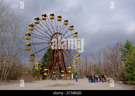 Pripjat, Ukraine, 14. März 2020. Touristen in der Nähe der berühmten Riesenrad in einem verlassenen Vergnügungspark in Pripyat. Wolkiges Wetter, der Himmel ist bedeckt Stockfoto