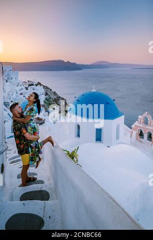 Santorini Griechenland, junges Paar auf Luxus-Urlaub auf der Insel Santorini beobachten Sonnenaufgang durch die blaue Kuppel Kirche und weiß Stockfoto