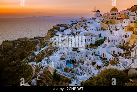 Sonnenuntergang auf der Insel Santorini Griechenland, wunderschönes weiß getünchtes Dorf Oia mit Kirche und Windmühle während des Sonnenuntergangs Stockfoto