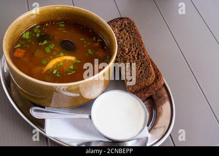 Traditionelle russische Fleischsuppe soljanka in einer Schüssel, mit saurer Sahne und schwarzem Brot. Krasnaja Poljana, Sotschi, Russland. Stockfoto