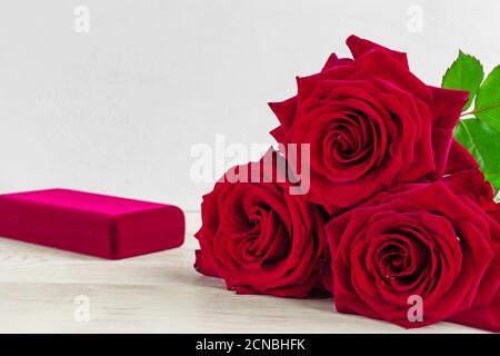 Schmuckschatulle und wunderschöne rote Rosen auf Holzhintergrund. Stockfoto