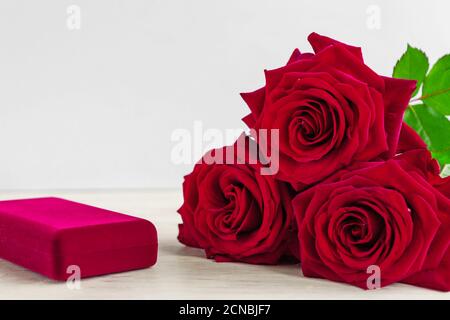 Schmuckschatulle und wunderschöne rote Rosen auf Holzhintergrund. Stockfoto