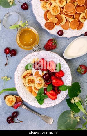 Porridge von winzigen Pfannkuchen mit Beeren, Sahne und Honig. Stockfoto