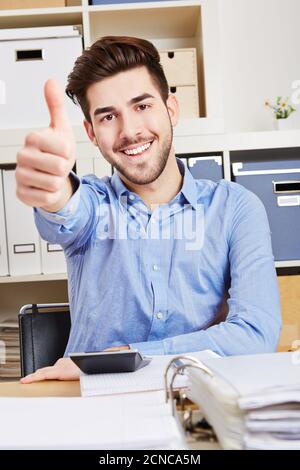 Erfolgreicher Lachender im Büro hält den Daumen hoch Stockfoto