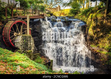 Vintage rotes Wasserrad mit Wasserfall im Glenariff Forest Park Stockfoto