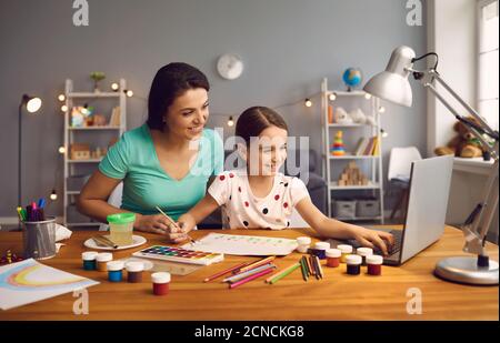 Online-Bildung von Kindern. Mutter und Tochter der Vorschule beobachten eine Video-Lektion Anruf Chat kreativen Kurs Kunst Zeichnung mit lapott zu Hause. Stockfoto