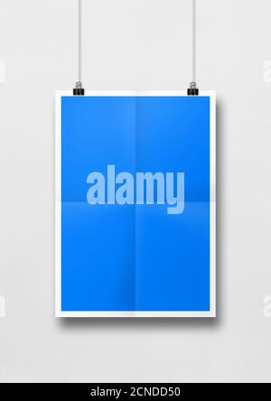 Blaues gefaltetes Poster, das an einer weißen Wand mit Clips hängt. Leere Mockup-Vorlage Stockfoto