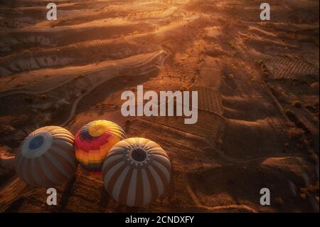 Goreme, Kappadokien, Türkei . Draufsicht auf bunte Heißluftballons, die bei Sonnenaufgang über dem Roten Tal fliegen. Stockfoto