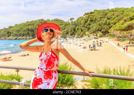 Glückliche Frau Tourist mit breiten roten Hut auf dem Dach am Fetovaia Strand, Insel Elba, Toskana, Italien, Europa Stockfoto