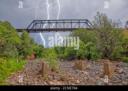 Blitz von einem Monsunsturm, der hinter einer alten Eisenbahnbrücke über den Bear Canyon in der Nähe von Perkinsville, Arizona, auffällt Stockfoto