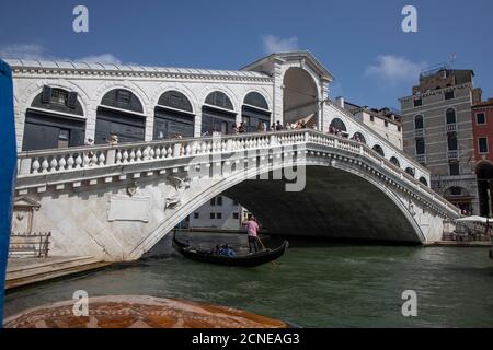 Gondoliere mit Touristen in Gondel unter der Rialtobrücke auf dem Grand Canal in Venedig, Italien, Europa. Stockfoto