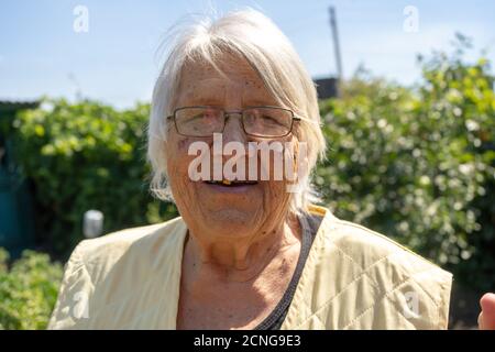 Alte Dame schönes Gesicht und graue Haare, ältere Frau in ihrem Garten, Großmutter lächelt aus der Nähe Stockfoto