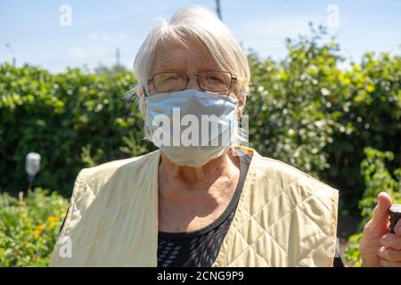 Alte Dame mit grauen Haaren tragen Schutzmaske, ältere Frau zu Hause in Quarantäne, Selbstisolation Stockfoto