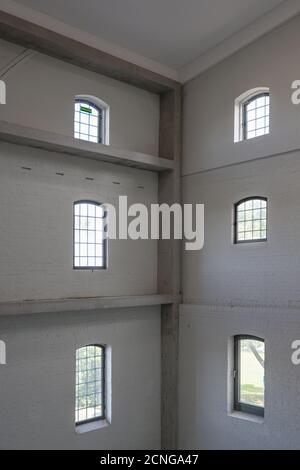 Grevesmühlen, Deutschland, 17. September 2020: Ecke in einem hohen ehemaligen Industriegebäude mit weißen Wänden, am oberen Fenster hängt ein absurder Notfall Stockfoto