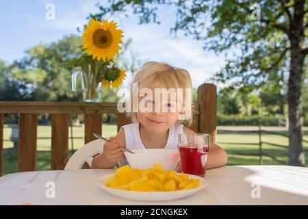 Kind, Kleinkind Junge, mit Frühstück am Morgen, sitzen auf der Veranda von Camping van, Reisen Sommerzeit, Familienurlaub Stockfoto