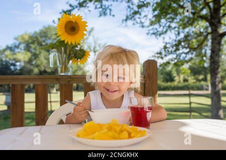 Kind, Kleinkind Junge, mit Frühstück am Morgen, sitzen auf der Veranda von Camping van, Reisen Sommerzeit, Familienurlaub Stockfoto