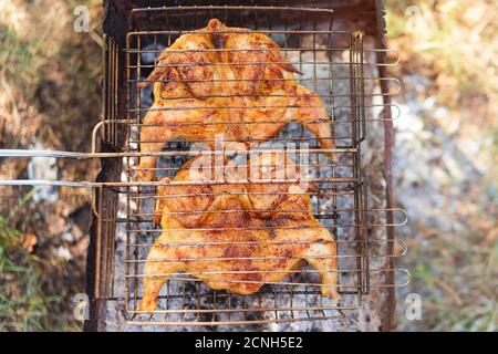 Gebratenes und gegrilltes Hähnchen auf dem Grill im Freien aus nächster Nähe. Chicken Tabaka oder Tapaka ist ein traditionelles georgisches Gericht Stockfoto