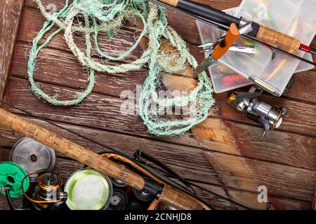 Verschiedene Angeltacles mit Rute und Rollen auf hölzernem braunem Hintergrund. Mockap für Werbung und Veröffentlichung. Stockfoto