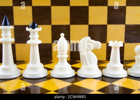 Weiße Schachfiguren stehen vor dem Hintergrund des Schachbretts Stockfoto