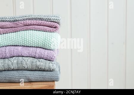 Stapel von gemütlichen Strickpullover auf einer Holzleiter. Skandinavischer Stil. Weiße Holzwand Stockfoto