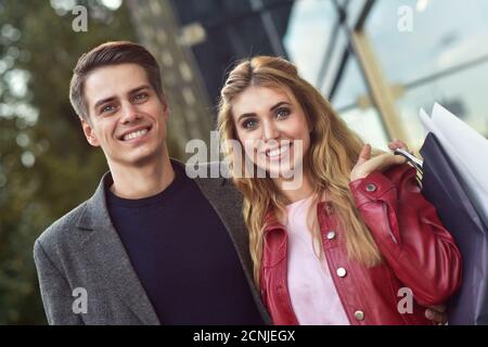 Schöne junge Liebende paar Durchführung Einkaufstüten und gemeinsam genießen. Bild junges paar Shopping in der Stadt. Stockfoto