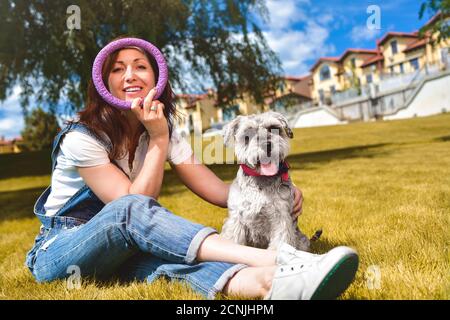 Kaukasische fröhliche Frau spielt mit ihrem geliebten Hund im Park. Das Konzept der Liebe zu Tieren. Beste Freunde. Hunderasse Schnau Stockfoto