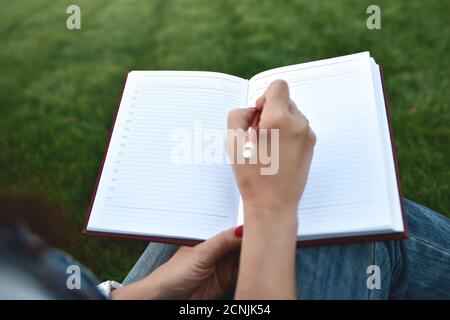 Nahaufnahme junge Frauen schreiben auf Notebook im Park, Konzept in Bildung und Wissen Stockfoto