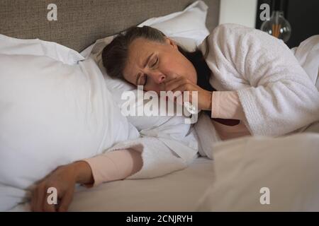 Kranke kaukasische Frau, die Zeit zu Hause verbringt, soziale Distanzierung und Selbstisolation in Quarantänesperre, im Bett liegend, hustet. Stockfoto