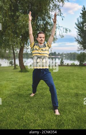 Mann Durchführung Yoga junge Fitness Mann im Freien tun Übung. Bein strecken. Sommerzeit Stockfoto