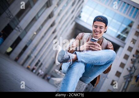 Fröhlicher Mann, der Musik mit Kopfhörern von einem Smartphone auf der Straße hört. Stockfoto