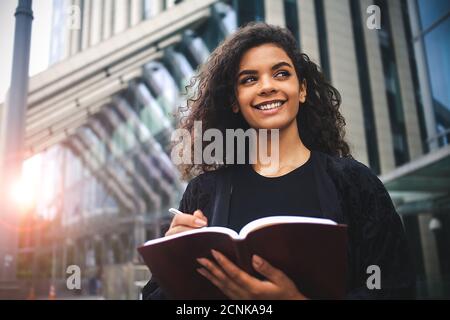 Porträt einer schwarzen Frau, die Notizen auf der Straße schreibt Stockfoto