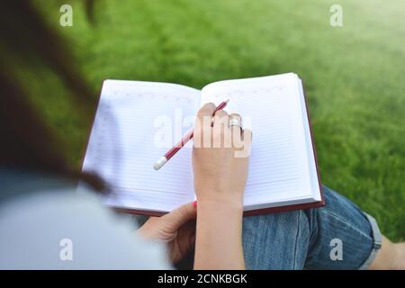 Nahaufnahme junge Frauen schreiben auf Notebook im Park, Konzept in Bildung und Wissen Stockfoto