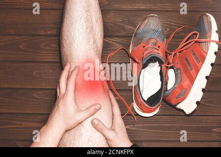 Junge Sportmann mit starken sportlichen Beinen halten Knie mit Seine Hände Schmerzen nach einer Bandverletzung während einer Läuft w Stockfoto
