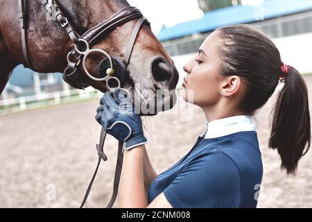 Nahaufnahme der Jockey Frau umarmt ein Pferd. Junges Mädchen streicheln ihr Pferd im Stall. Konzept der Pferdentherapie. Liebe zwischen Peo Stockfoto