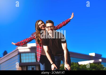 Junge lächelnde Paar mit Spaß Huckepack Reiten auf der Straße. Stockfoto