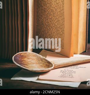Kochrezept Buch auf Holztisch Hintergrund. Altes Vintage Kochbuch und Holzpfanne Nahaufnahme, vertikal Stockfoto
