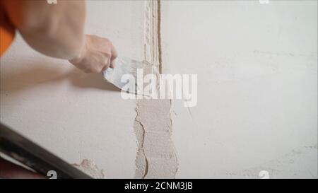 Dekorative Gipsbeschichtung. Der Mensch tut zerlumpte Textur an der Wand mit einem Spachtel. Gipsauftrag an der Wand Stockfoto