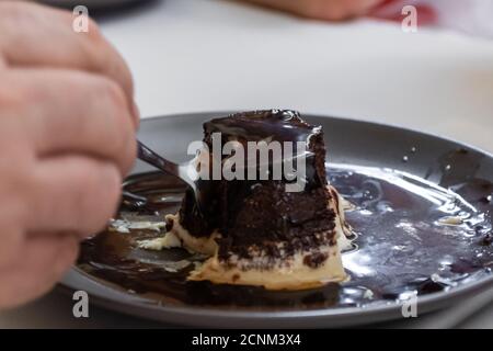Nahaufnahme der Hand einer Person mit einem Löffel zu Essen Sie ein Stück Kuchen Stockfoto