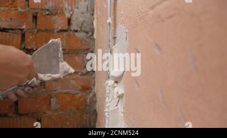 Dekorative Gipsbeschichtung. Der Mensch tut zerlumpte Textur an der Wand mit einem Spachtel. Gipsauftrag an der Wand Stockfoto