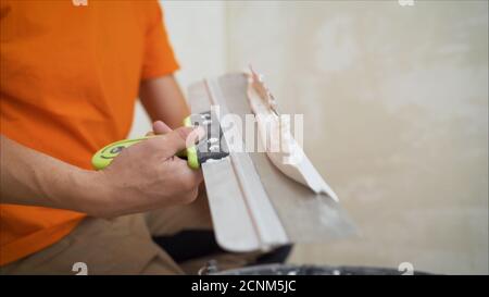 Arbeiter, der die Kelle zum Verputzen der Betonwand auf der Baustelle benutzt. Machen die Glätte und flach die Oberfläche der Zementwand aus Holz Stockfoto