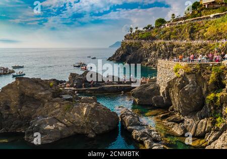 Schöne Panorama-Landschaft Blick auf das Küstengebiet in Manarola in der Nähe der Marina an einem sonnigen Tag mit blauem Himmel. Touristen folgen dem Weg nach oben... Stockfoto