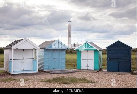 Gegenüberstellung von Calshot Spit Strandhütten, mit Fawley Power Station im Hintergrund. Stockfoto