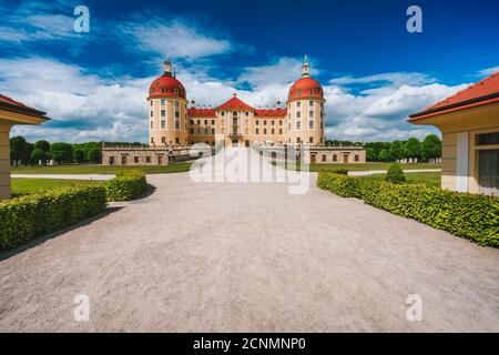 Deutschland, Sachsen Region, Dresden, Schloss Moritzburg. Schöner Frühlingstag mit blauem Himmel und weißen Wolken. Fußweg führt zu Schloss und Park. Stockfoto