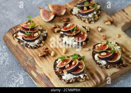Toast mit Feigen, Honig, Käse und Nüssen auf rustikalem Holzbrett. Selektiver Fokus Stockfoto