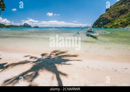 Schöne Landschaft von Corong Corong Strand mit traditionellen Boot und Palmen Schatten. El Nido, Palawan Island, Philippinen. Stockfoto